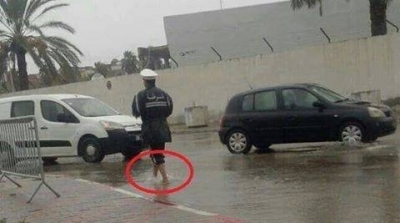 عون امن حافي القدمين وسط الامطار ينظم حركة المرور امام ثكنة صفاقس 